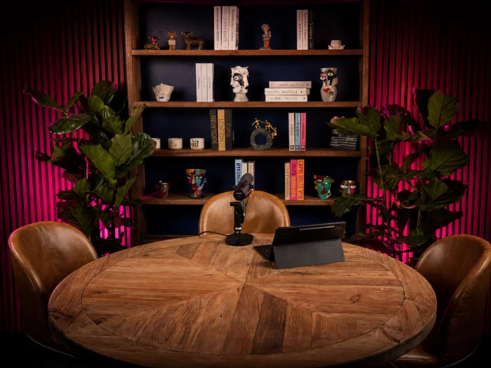 The bookshelf backdrop, dressed with books and ceramics, fiddle-leaf figs either side of the table